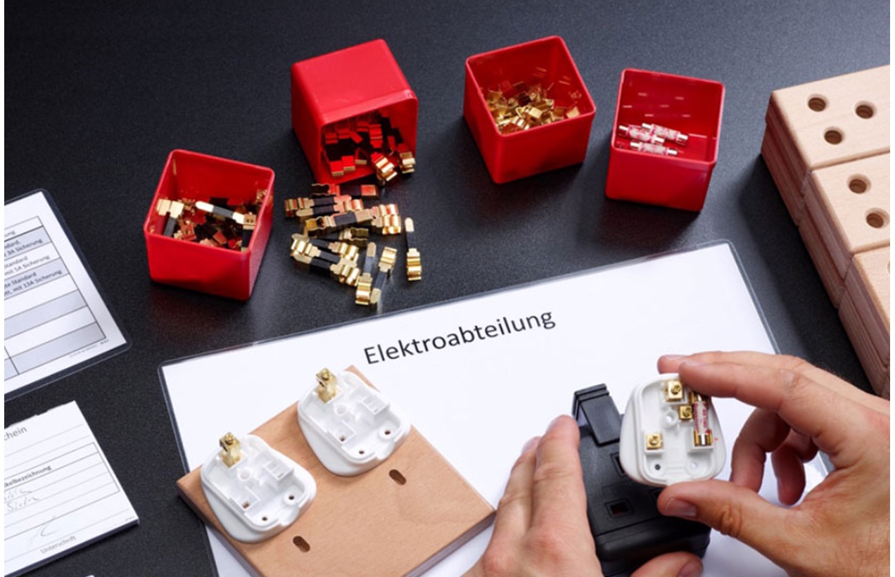 Lean Game: Teilnehmer montieren Stecker in der Produktionssimulation